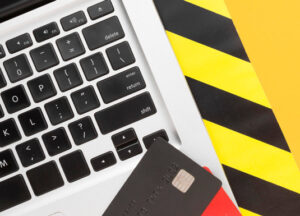 carte di credito, pc portatile e fascia gialla e nera di attenzione