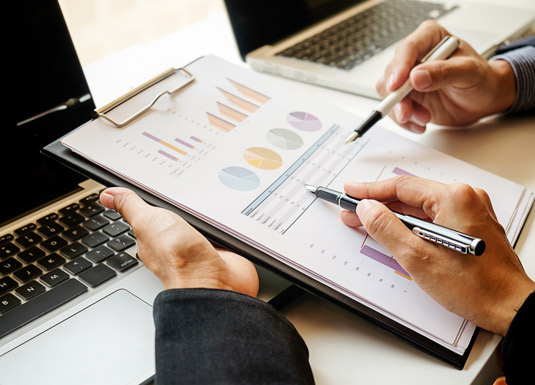 report cartaceo davanti a computer portatile